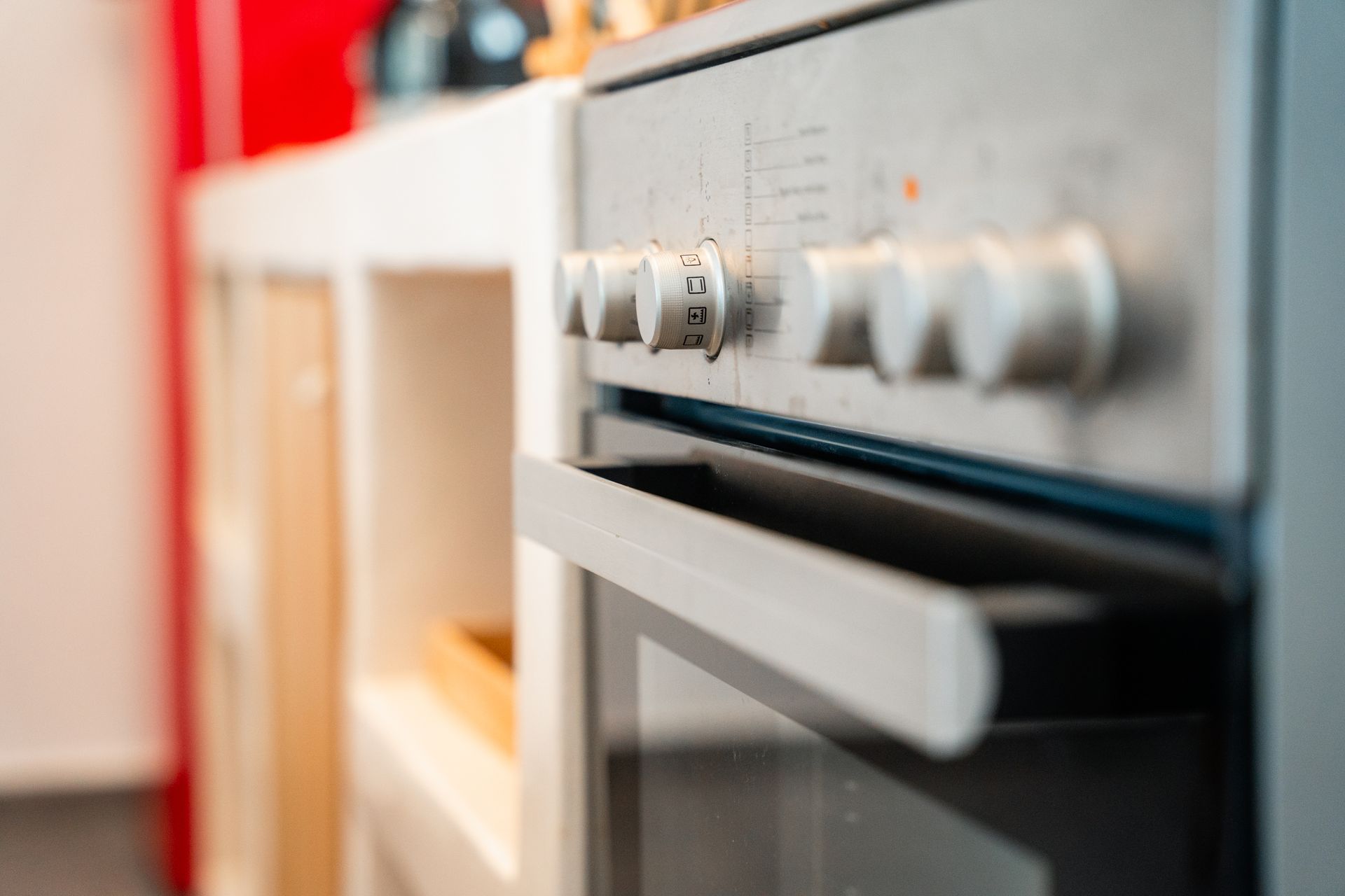 Close-up of a stove with knobs. The oven door is open slightly, showing the interior.
