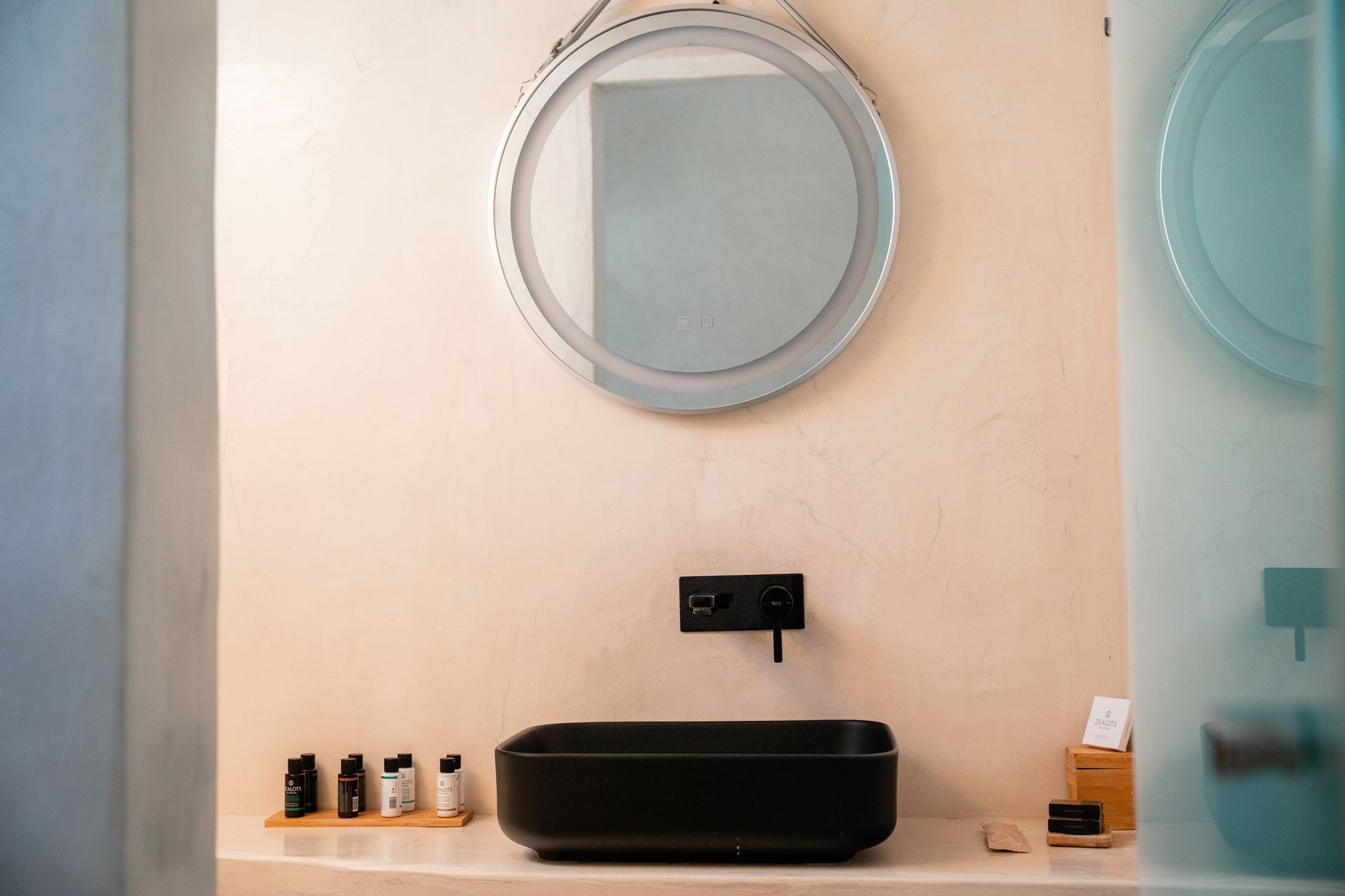 Bathroom sink with a round mirror and black fixtures.