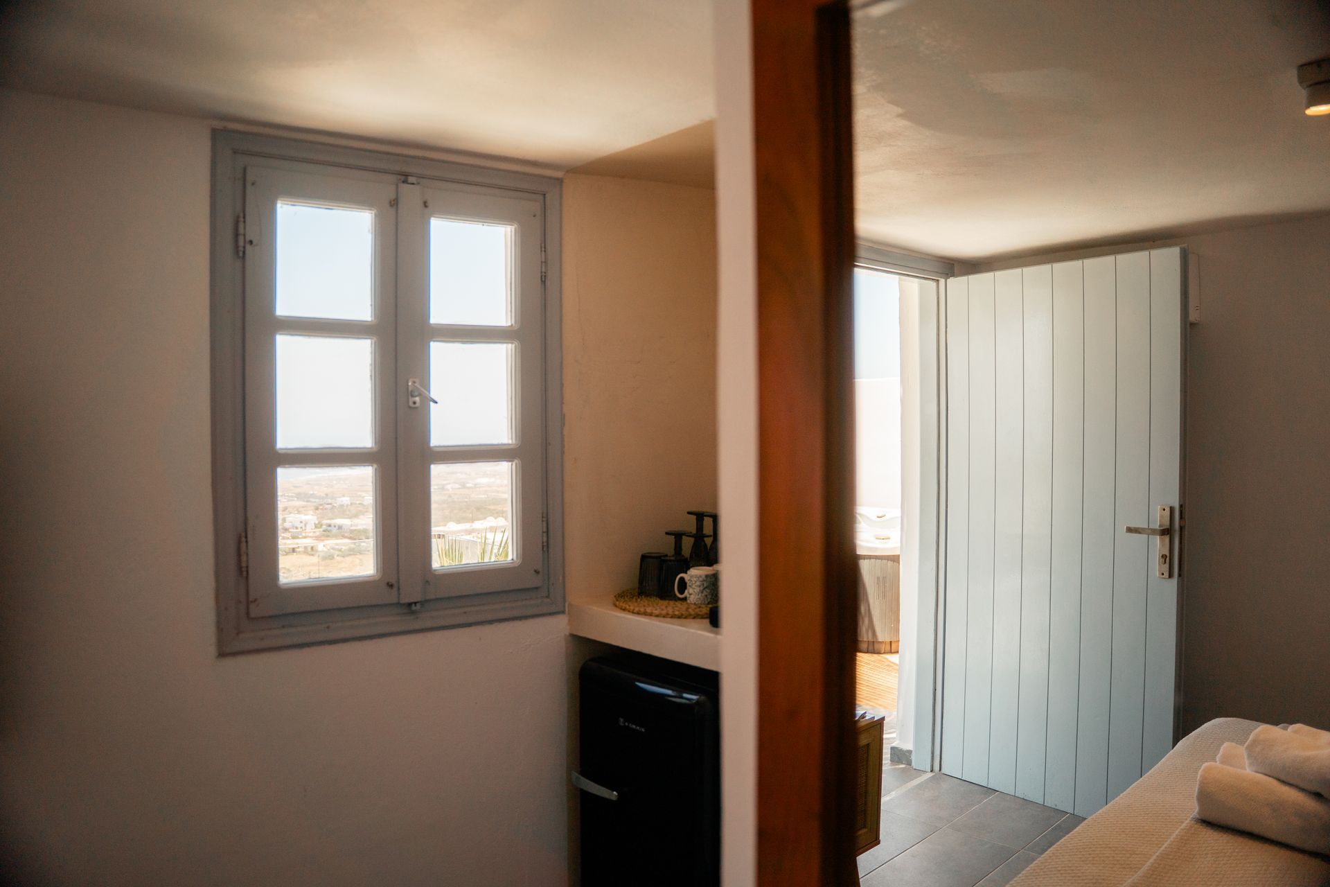 Room interior with a window, light blue door, and a mini-fridge. Sunlight streams through the window.