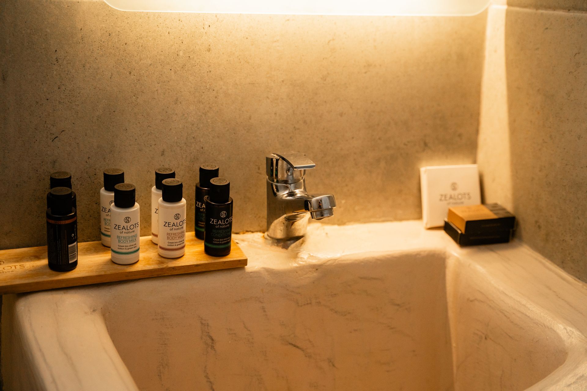 A bathtub with toiletries on a wooden tray and a silver faucet.