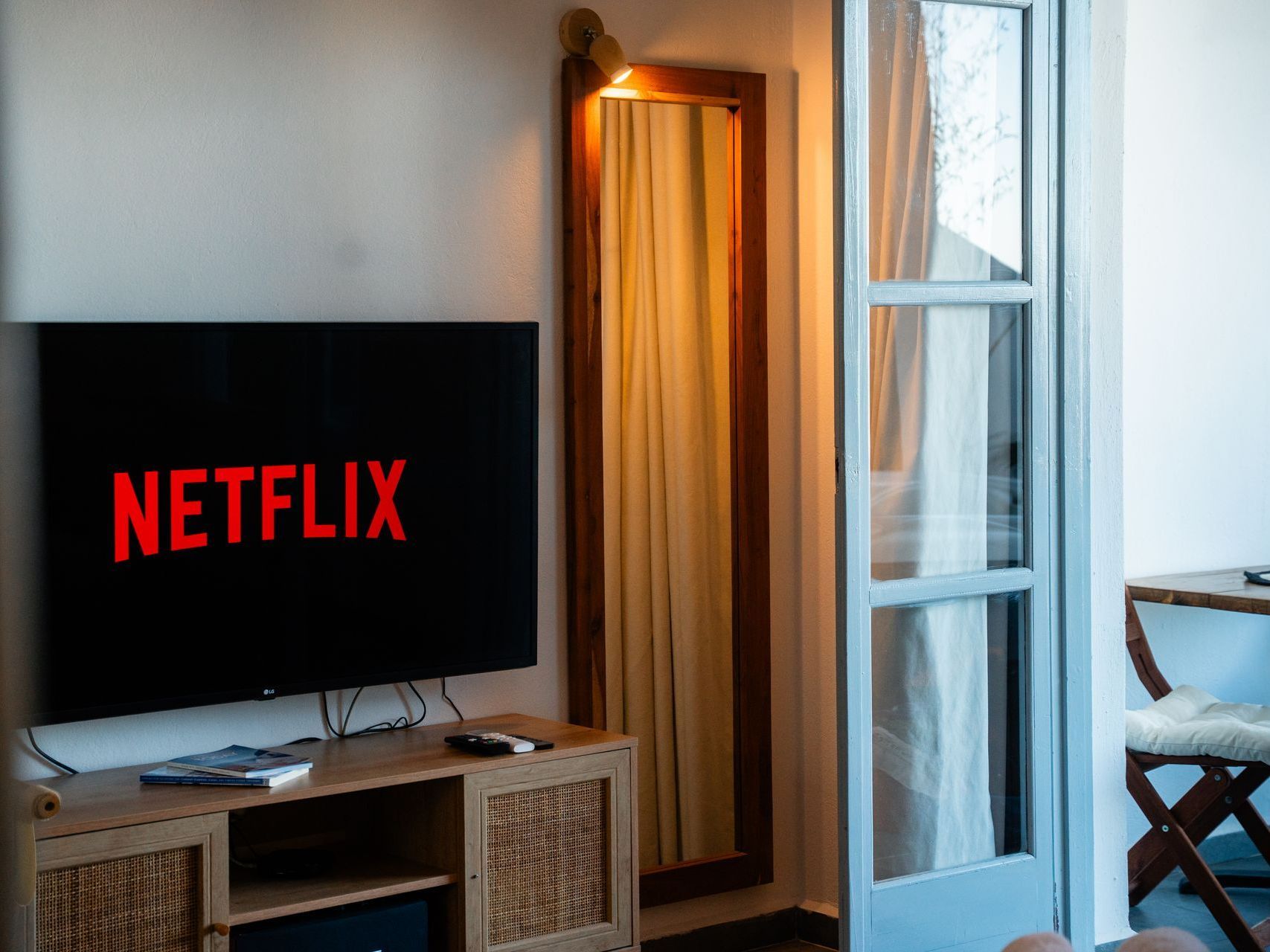 Netflix screen on a TV in a room with a mirror and balcony door.