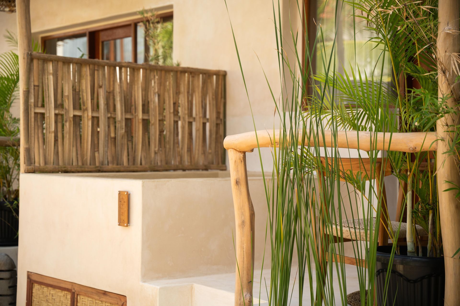 Exterior of a building with a white wall, wooden railing, and green plants.