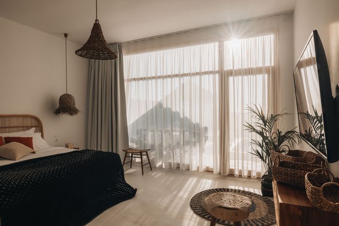 Bright bedroom with large windows, a bed, and woven decor.