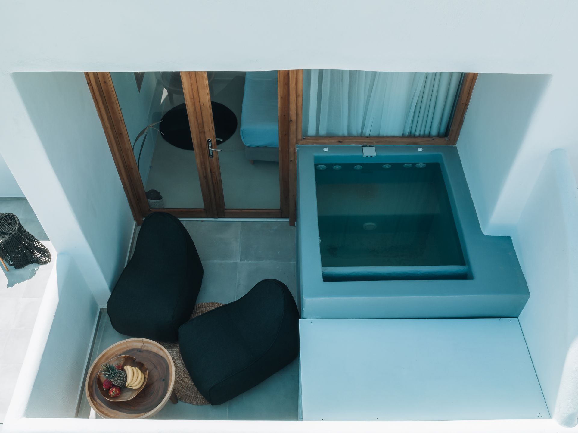 Balcony with hot tub, black beanbag chairs, and a wooden door. White walls.