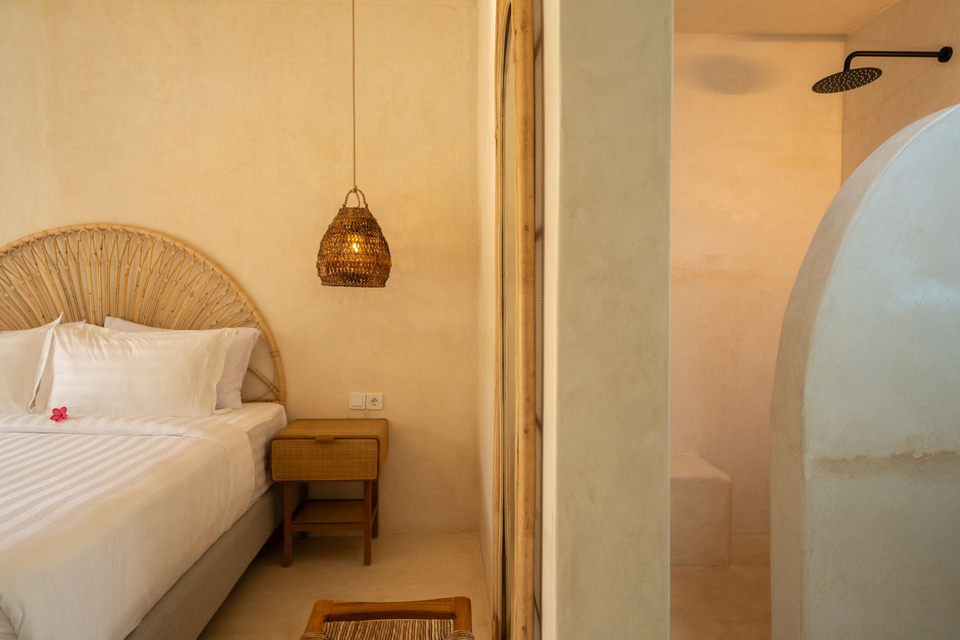 Bedroom with bed, woven headboard, nightstand, hanging light, and shower.