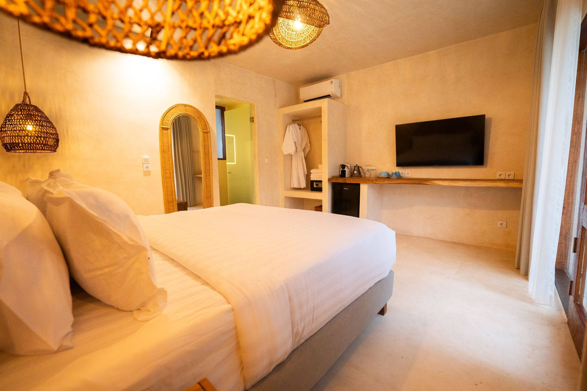 Bedroom with bed, TV, and archway to bathroom. Neutral colors with wooden accents.