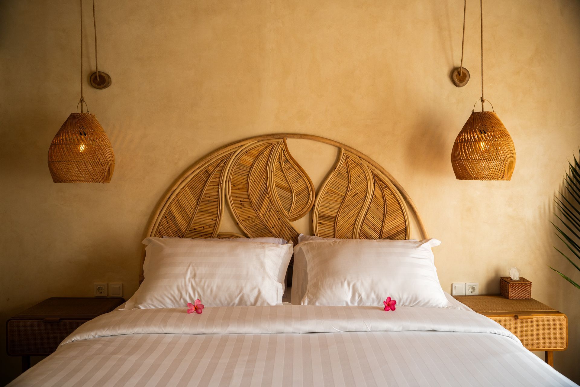Bedroom with woven headboard, white bedding, and woven pendant lights.