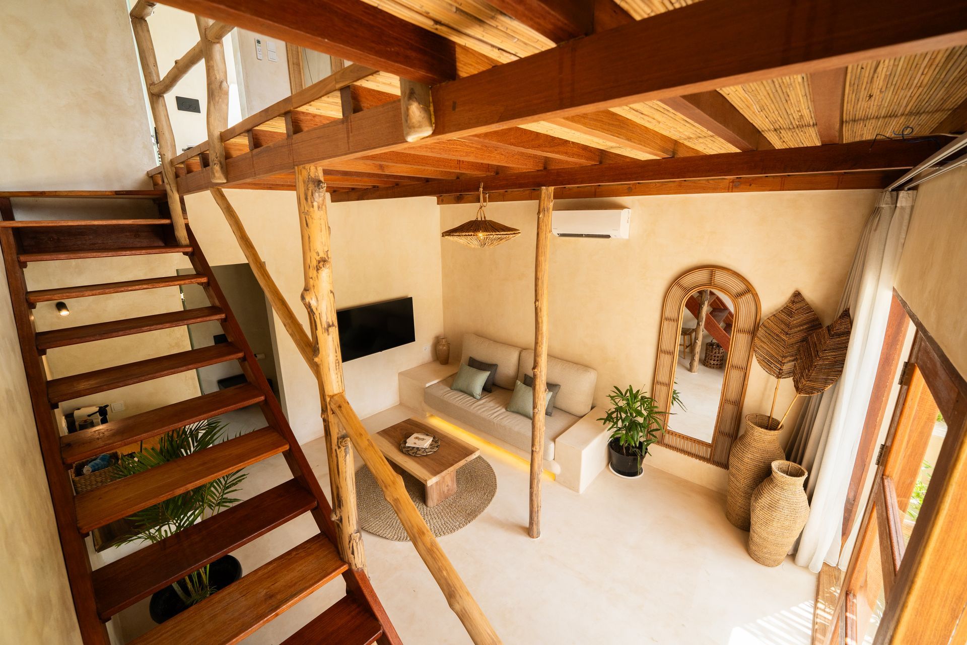 Wooden loft apartment with stairs, a couch, a mirror, and a TV.
