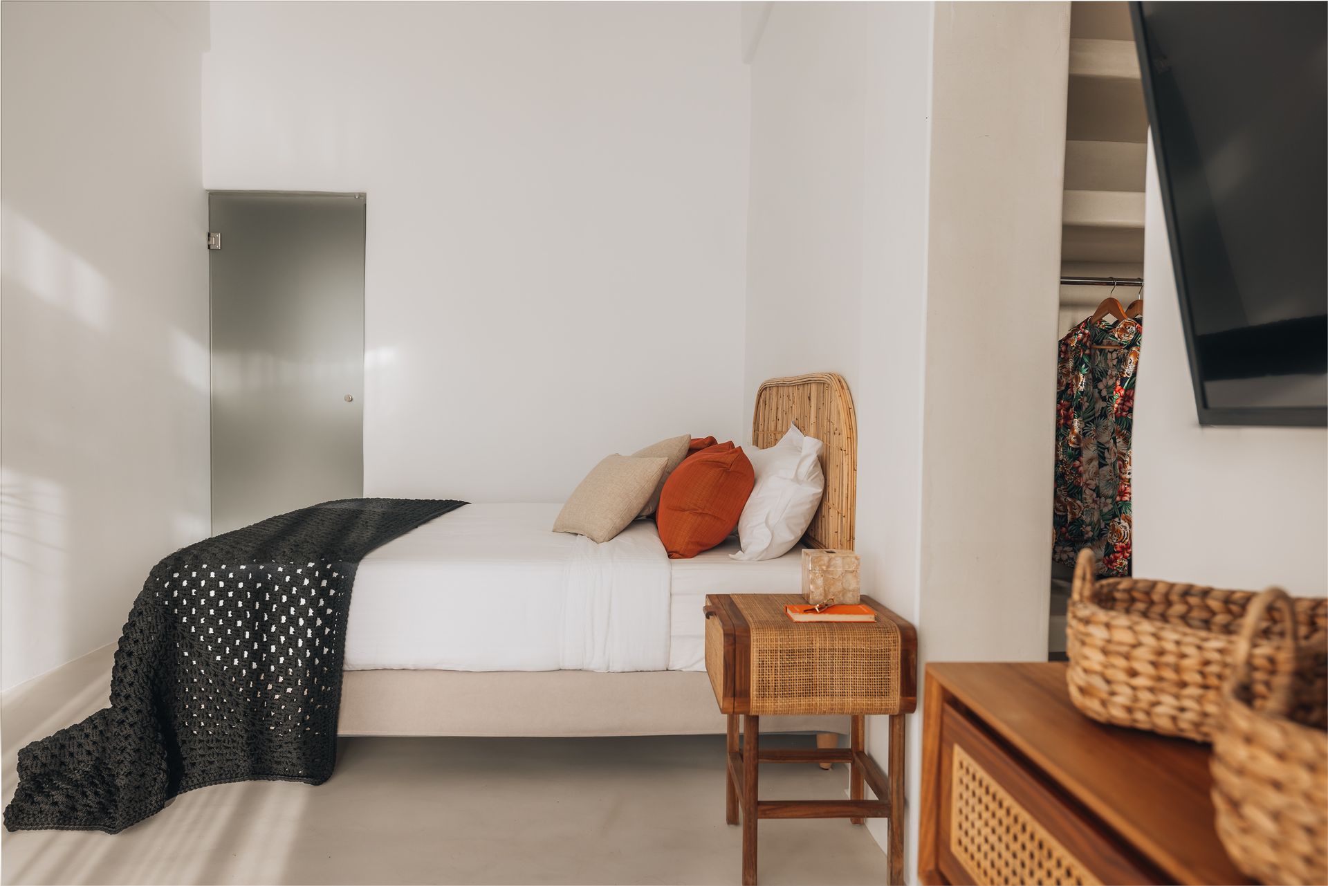 A cozy bedroom with a bed, woven headboard, nightstand, and built-in closet.