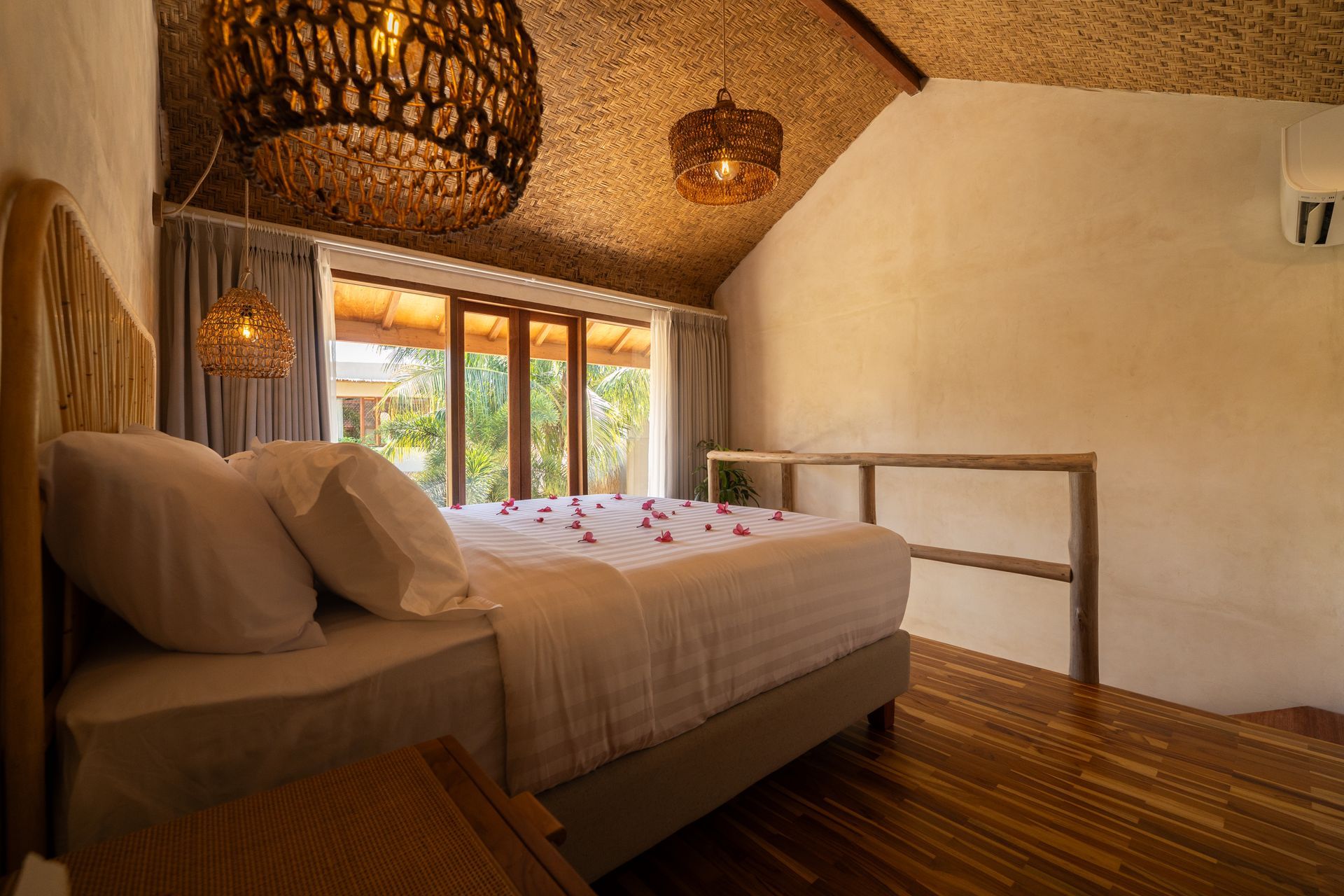 Bedroom with bed, decorative lighting, and large windows overlooking greenery.