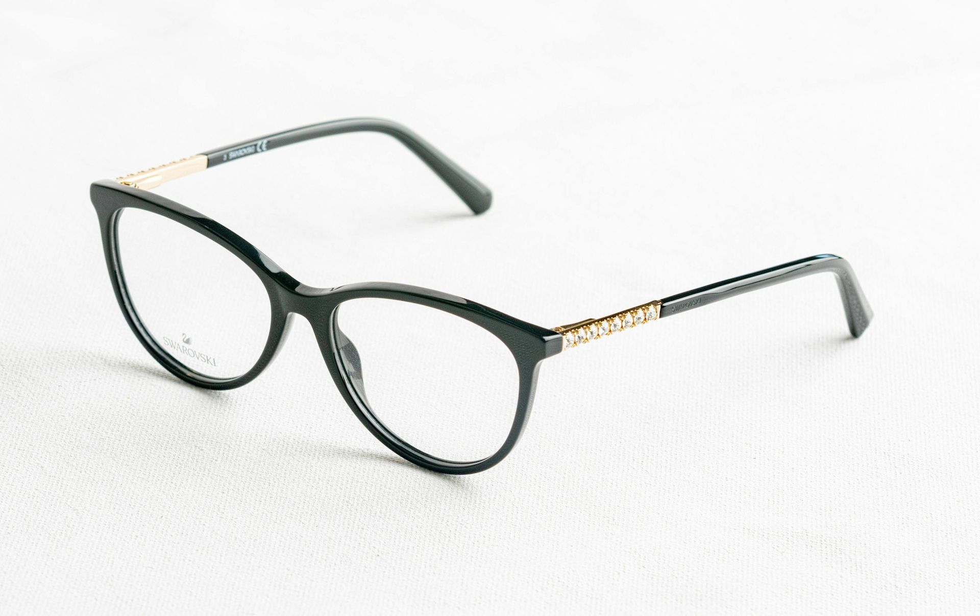 Black eyeglasses with gold accents on white surface.