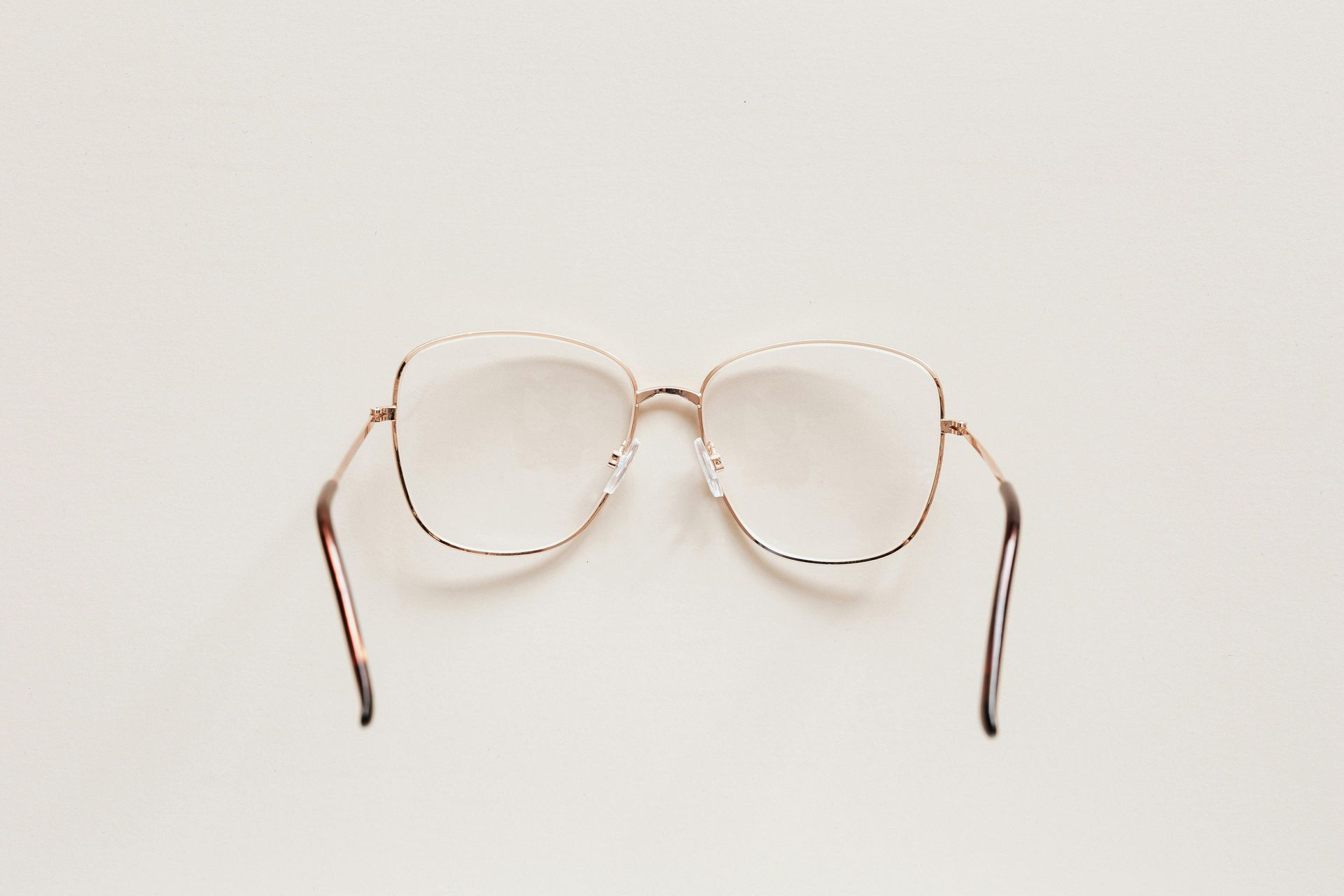 Gold-rimmed eyeglasses with large, square lenses against a white background.