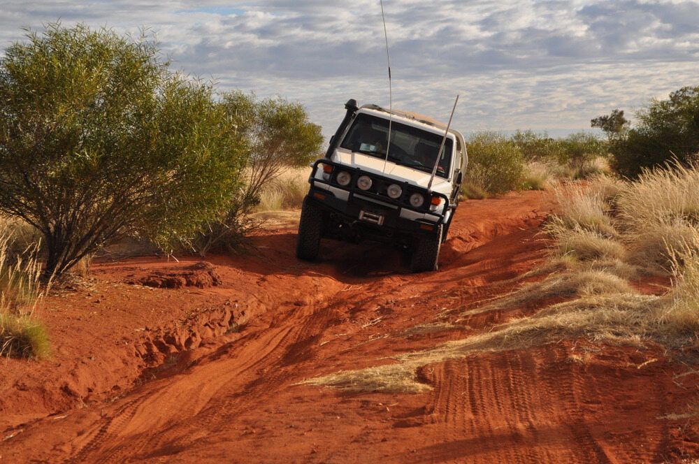 A White SUV Is Driving Down A Dirt Road In The Desert — Wilson's Towing In Pittsworth, QLD