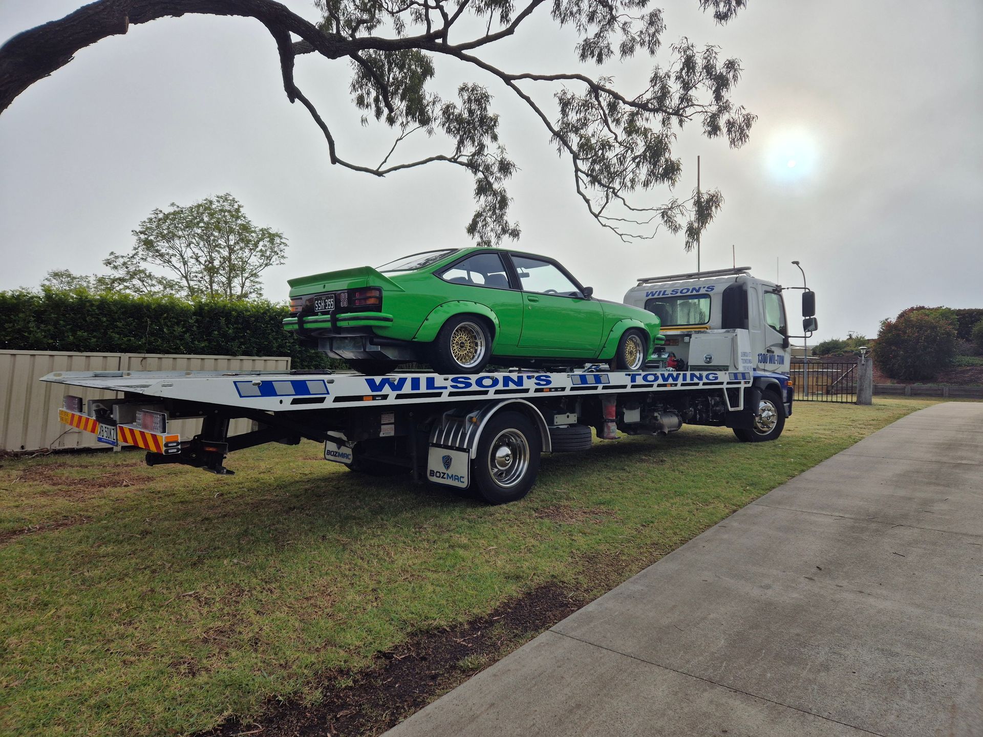 Green Car is Being Towed by a Tow Truck — Wilson's Towing In North Toowoomba, QLD