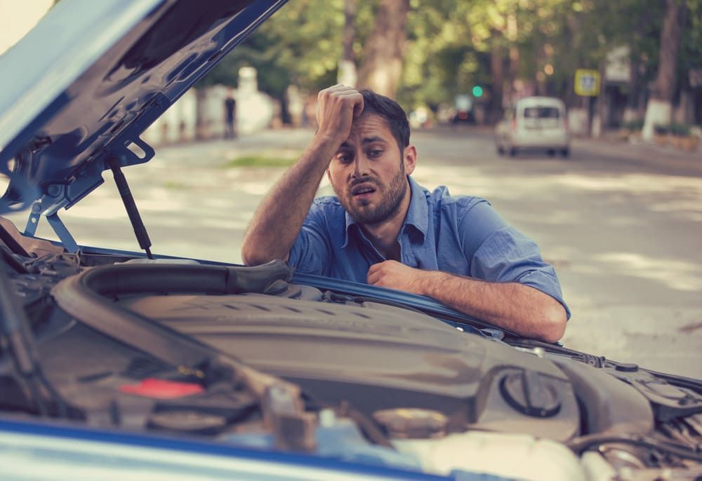 A Man Is Looking Under The Hood Of A Broken Down Car — Wilson's Towing In Maleny, QLD