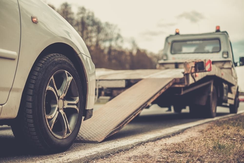 A Car Is Being Towed By A Tow Truck On The Side Of The Road — Wilson's Towing In Crows Nest, QLD
