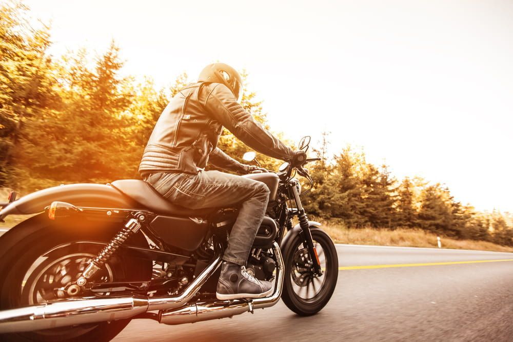 A Man Is Riding A Motorcycle Down A Road — Wilson's Towing In North Toowoomba, QLD