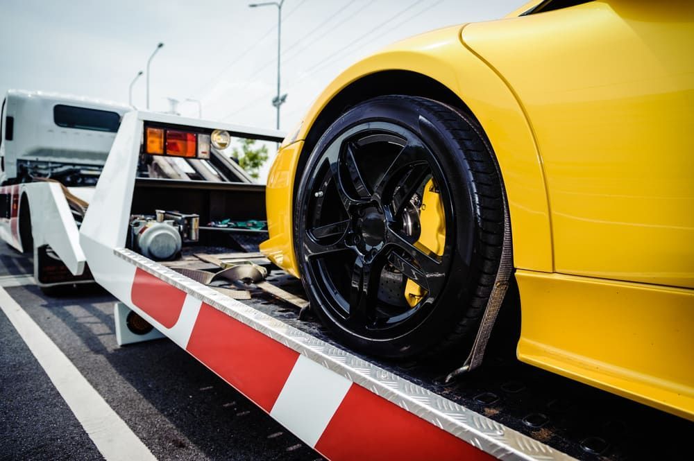 A Yellow Sports Car Is Being Towed By A Tow Truck — Wilson's Towing In Esk, QLD