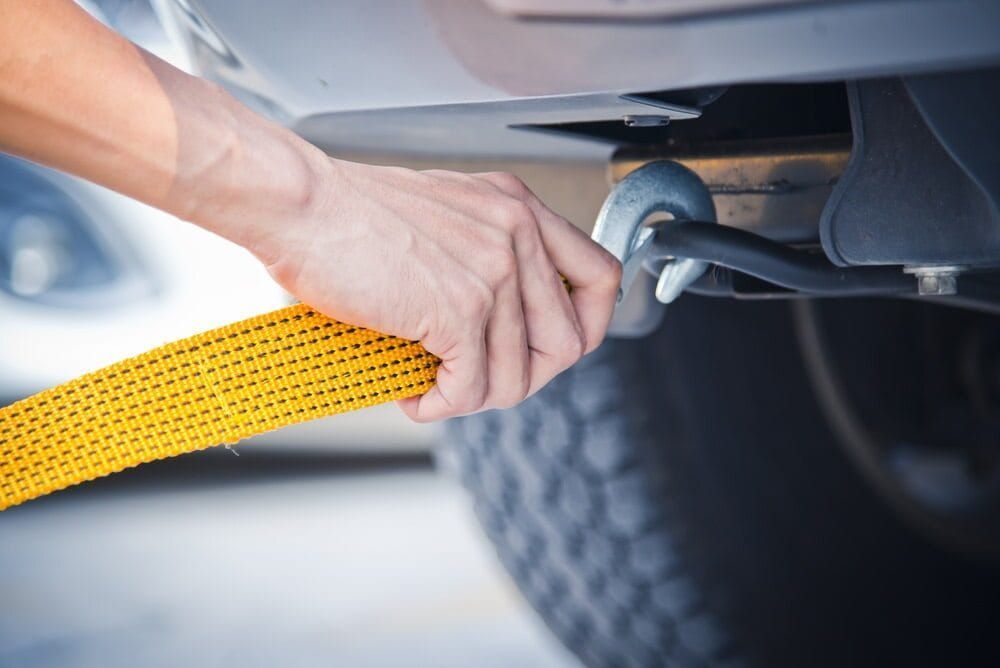 A Person Is Towing A Car With A Yellow Tow Strap — Wilson's Towing In St George, QLD