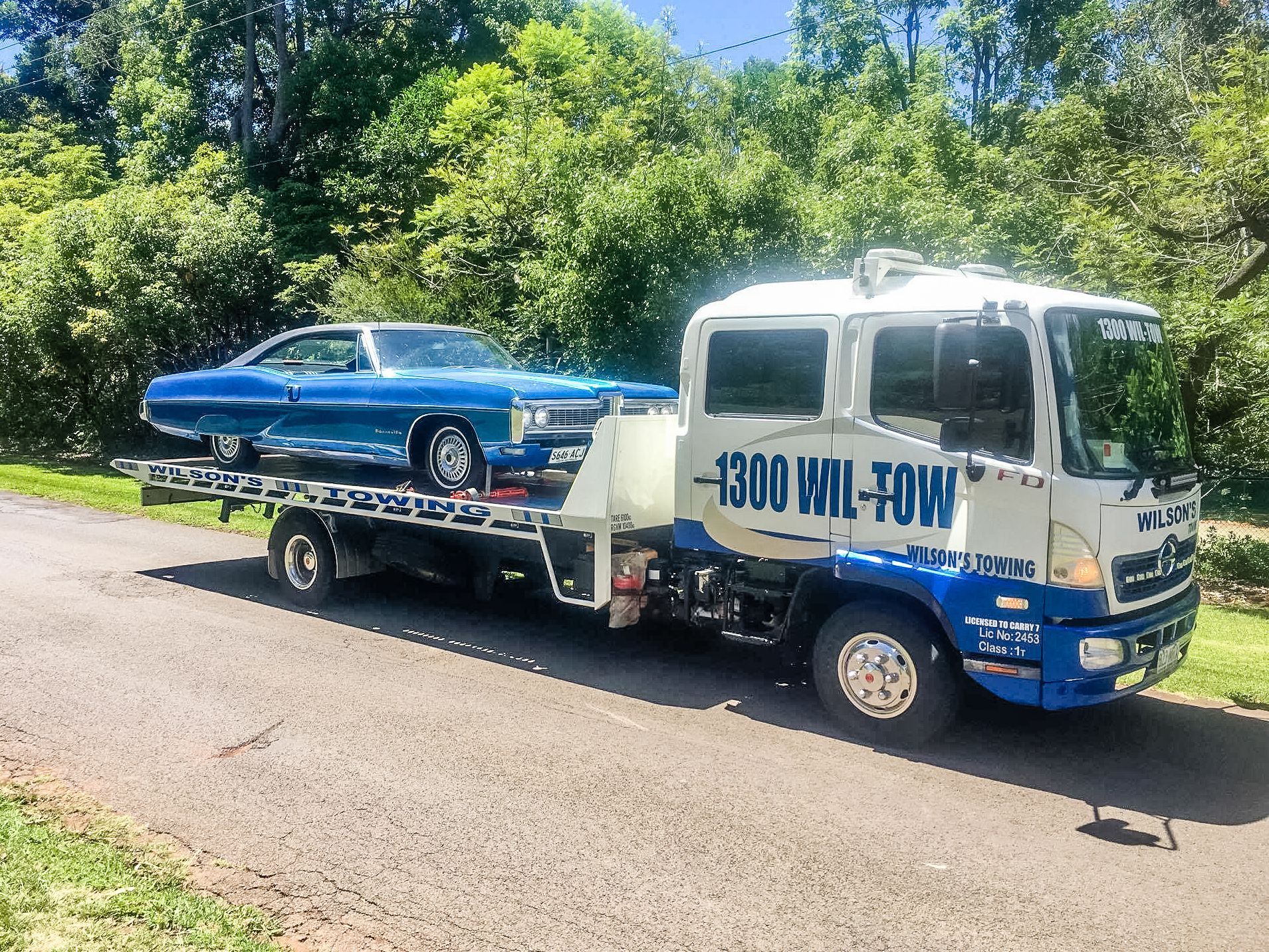 A Tow Truck Towing A Blue Car — Wilson's Towing In North Toowoomba, QLD