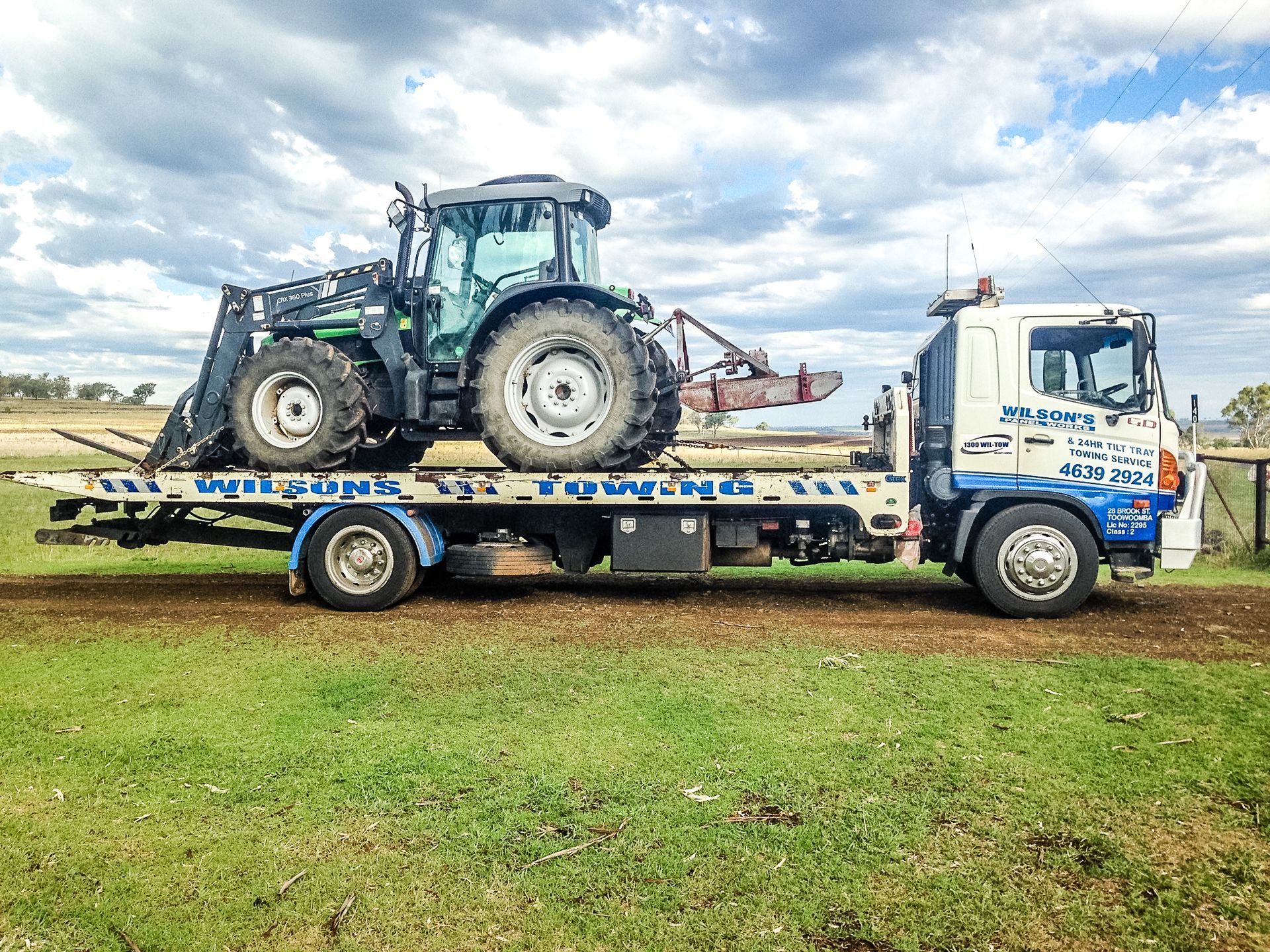 A Tow Truck Is Towing A Tractor— Wilson's Towing In North Toowoomba, QLD