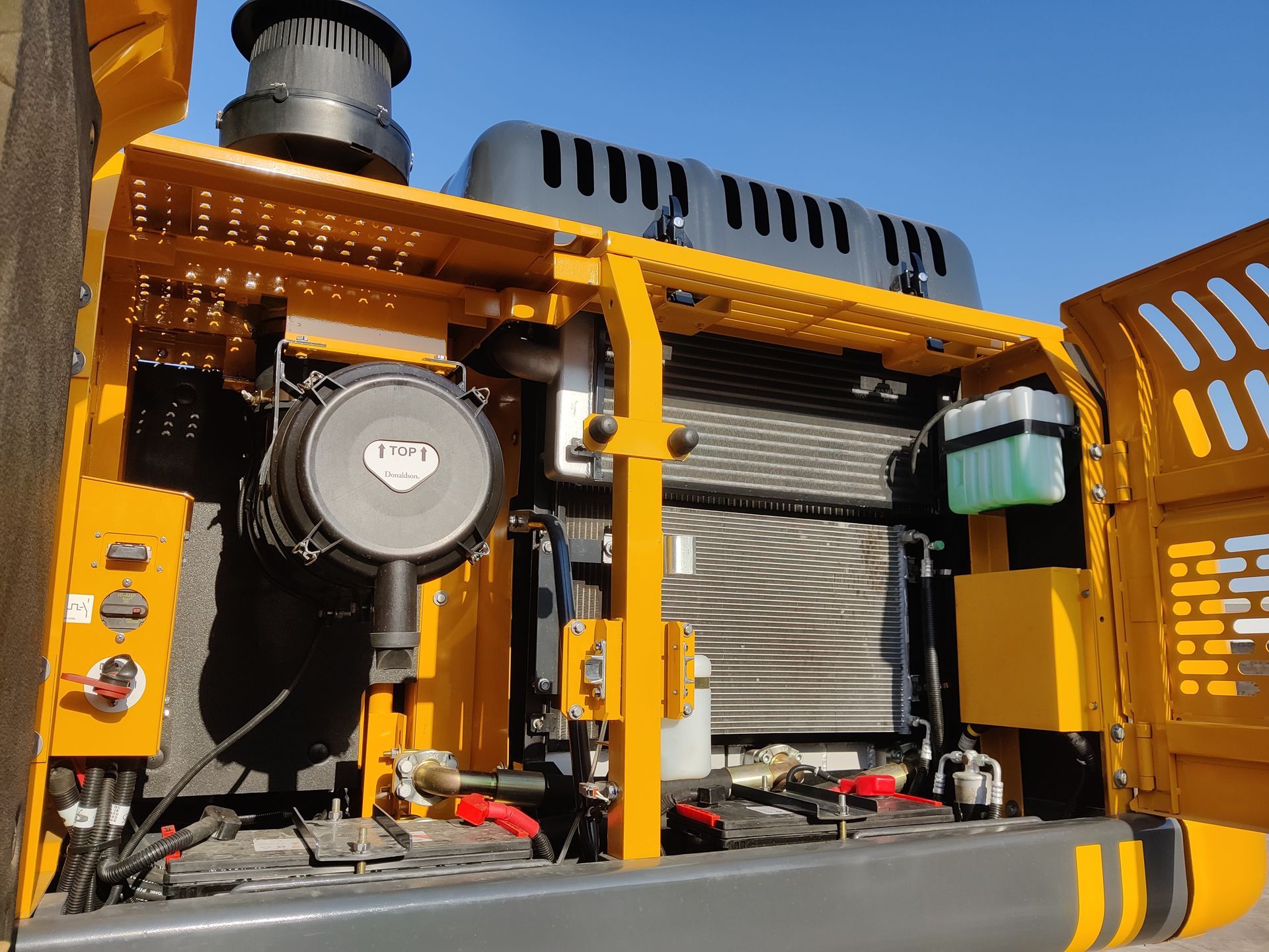 Yellow YUCHAI YC215 excavator engine compartment with air filter, radiator, and fluid reservoirs.