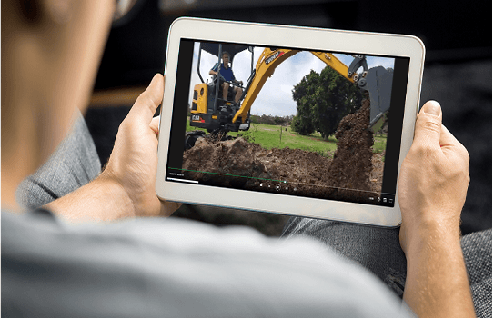 Person watching YUCHAI excavator video on tablet.