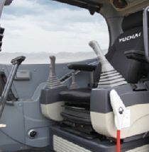 Interior of a Yuchai excavator cab with control levers and seat. Gray and tan colors.