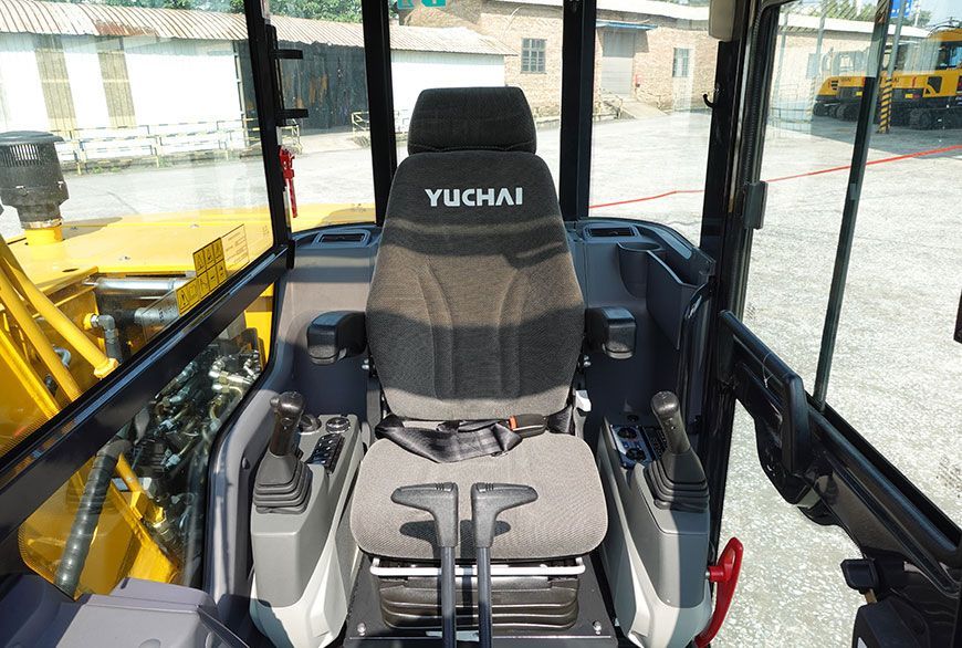 Interior view of a YUCHAI YC80 excavator cab, featuring a seat, joysticks, and control panel.