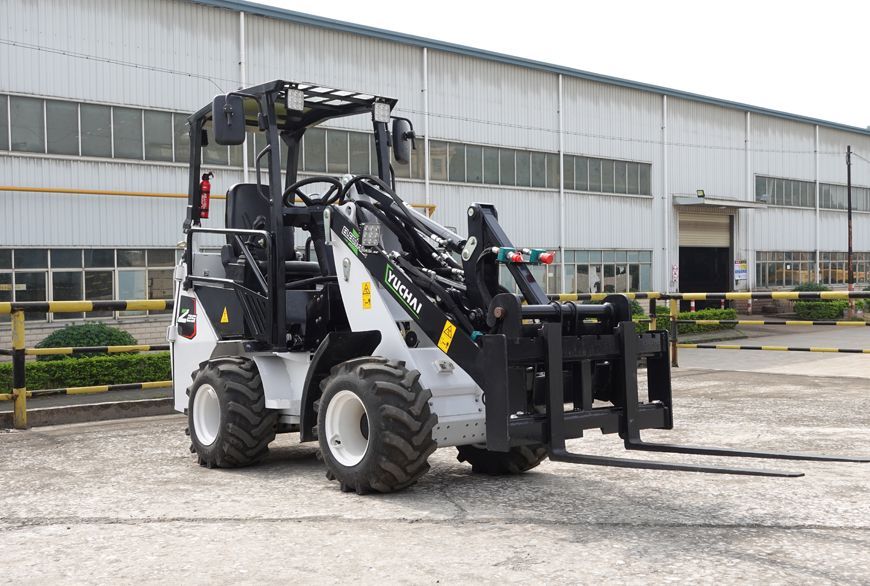 YUCHAI Z25 Compact white and black forklift with forks, parked in front of a factory.