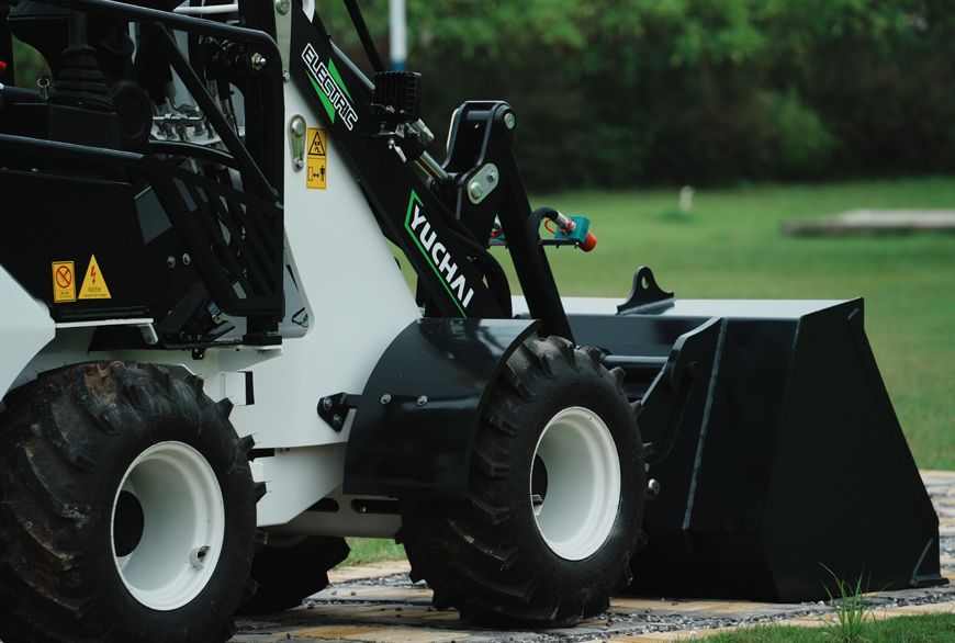 White and black YUCHAI Z25 mini loader with a black bucket, on a wooden platform.