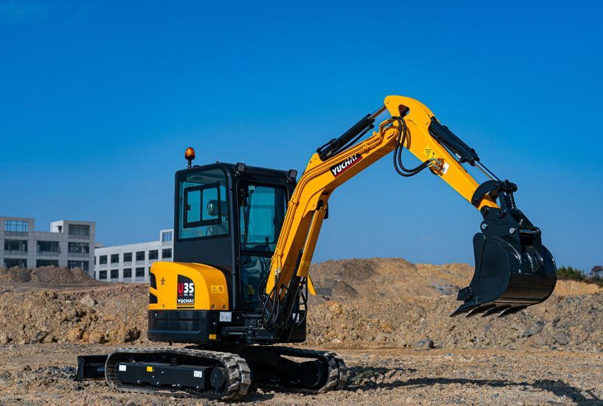 Yellow and black YUCHAI U35 mini excavator digging on a construction site with a blue sky.