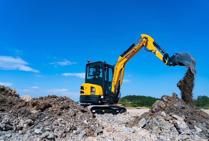 Yellow YUCHAI U35 excavator digging earth against a blue sky.