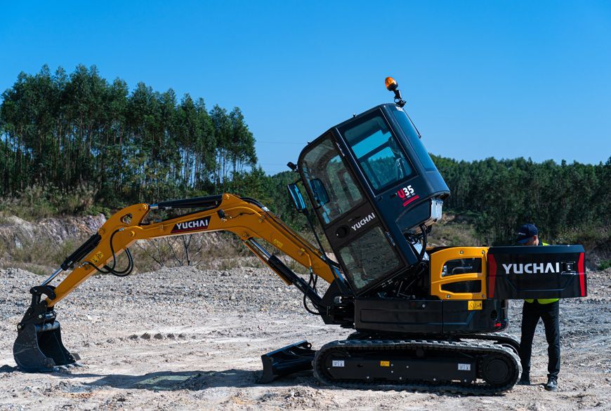 Yellow YUCHAI U35 excavator on tracks with a raised cab; a person stands nearby.