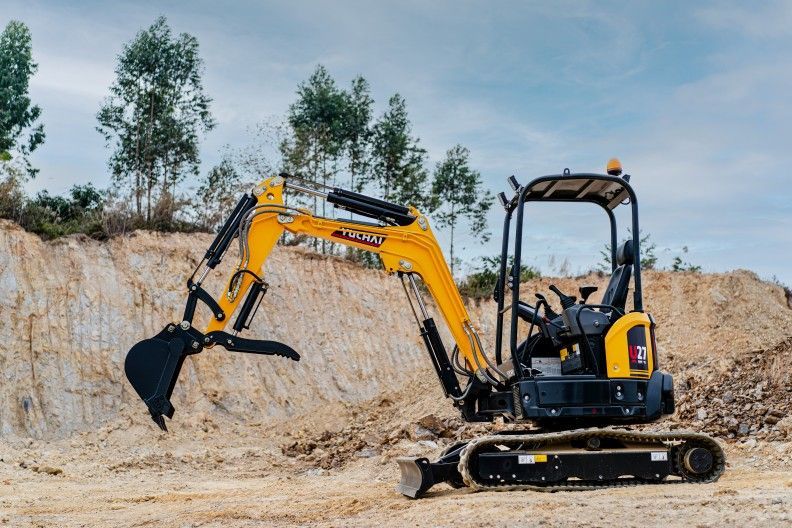 Une pelleteuse jaune creuse dans une fosse sous un ciel nuageux.