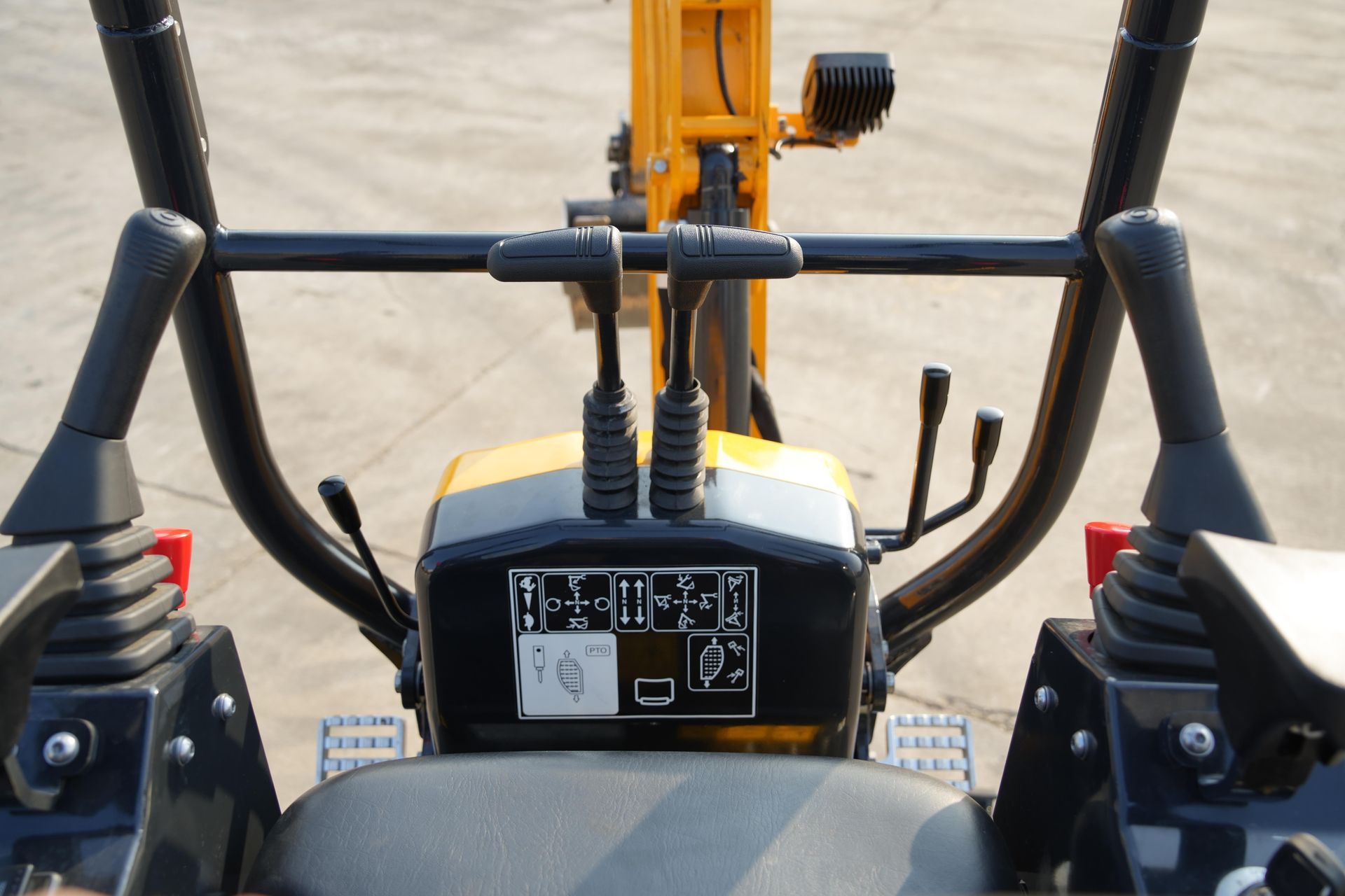 Commandes de l'excavatrice : leviers et joysticks noirs, panneau jaune, barres de sécurité noires, installation en extérieur.