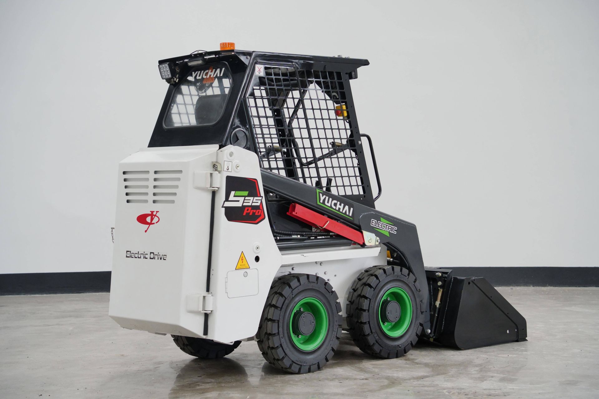 White and black YUCHAI S25 skid steer loader with green wheels and a black bucket, in a studio.