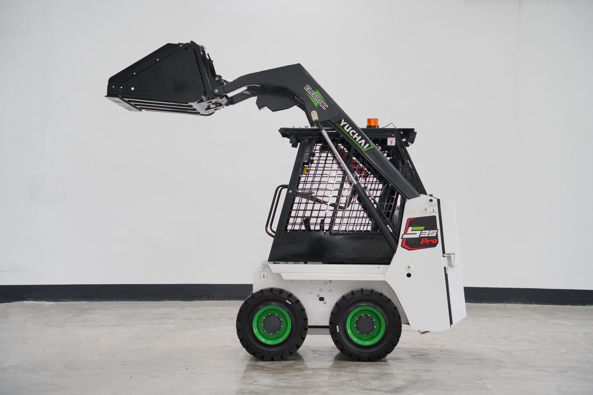White and black YUCHAI S25 skid steer loader with green wheels and raised bucket in a studio.