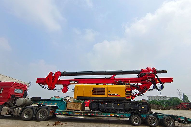 A large yellow and red YUCHAI drilling rig on a trailer, ready for transport.