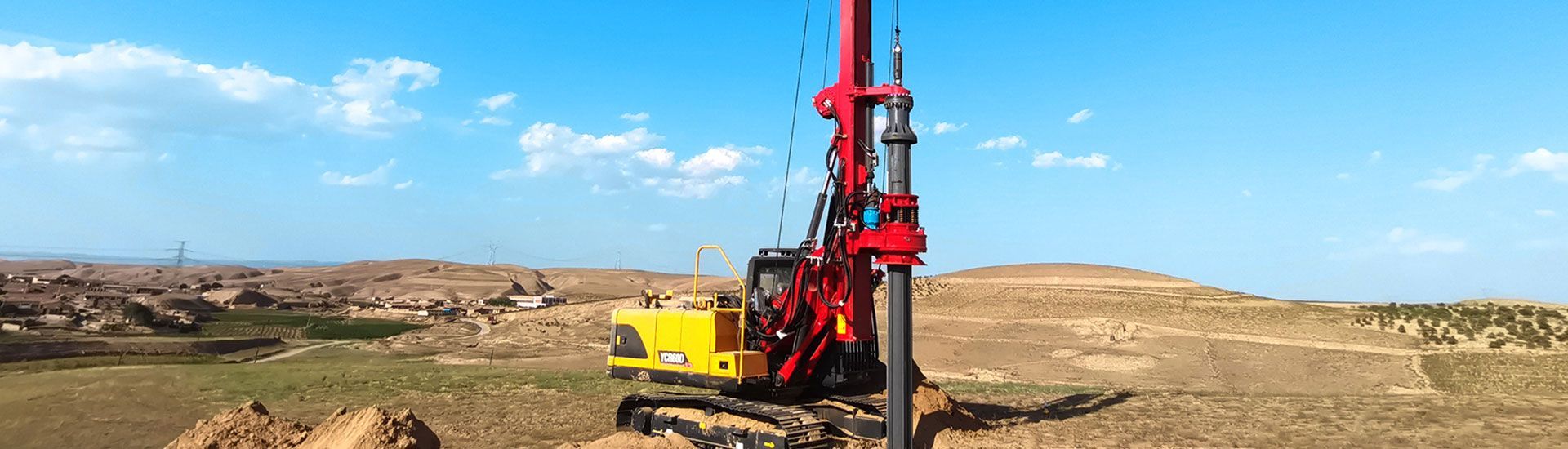 A large YUCHAI YCR65E drilling rig on a construction site under a bright blue sky.