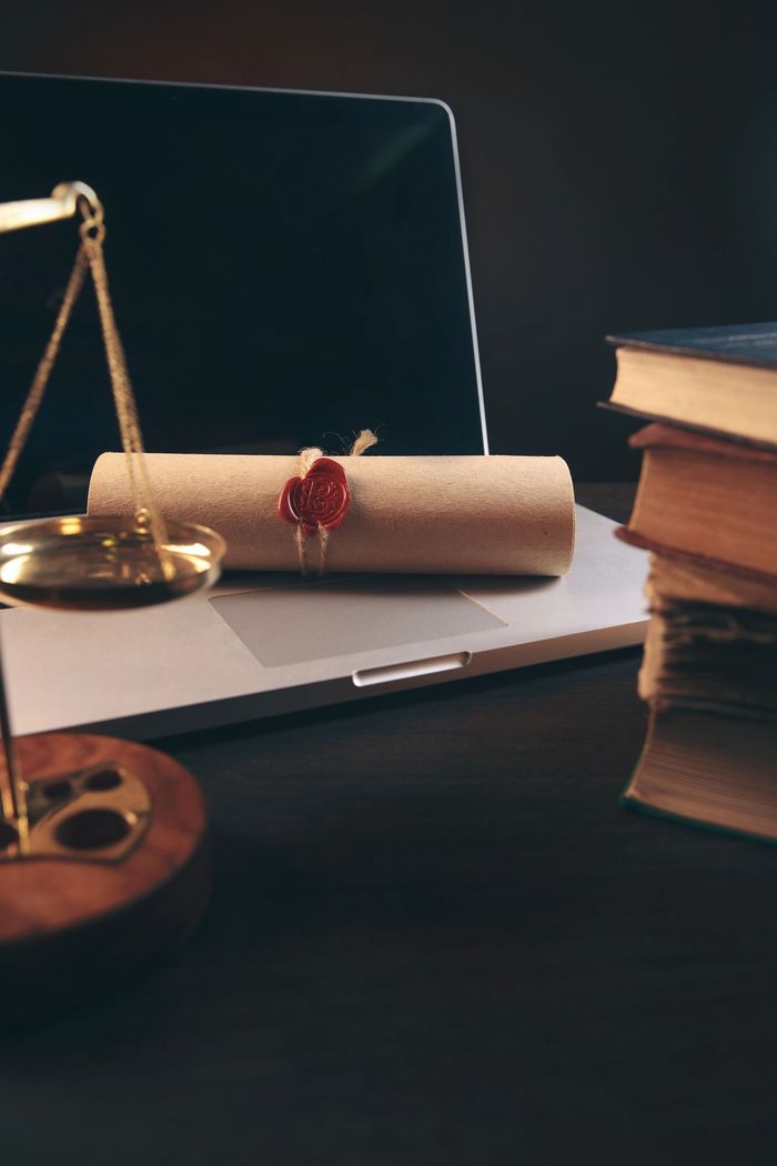 Bilancia accanto al portatile, rotolo di pergamena e pila di libri su una scrivania scura