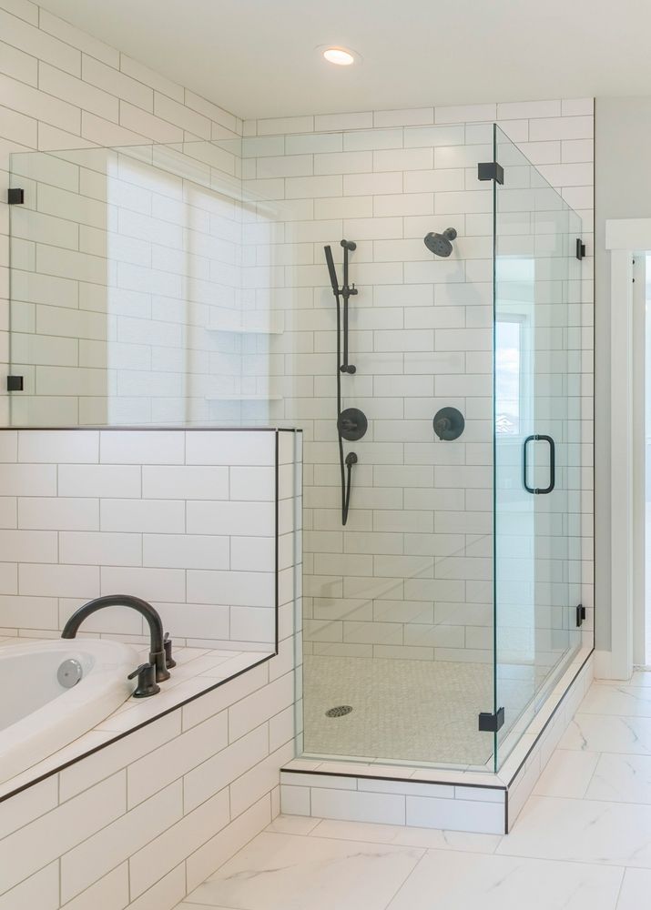 A bathroom with white tiles and a walk in shower.
