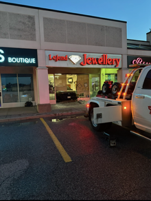 Liquor Jewelry storefront at dusk, with a tow truck parked in front of the entrance.