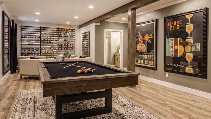 Basement with mounted TV, fireplace, beige sofas, and patterned rug