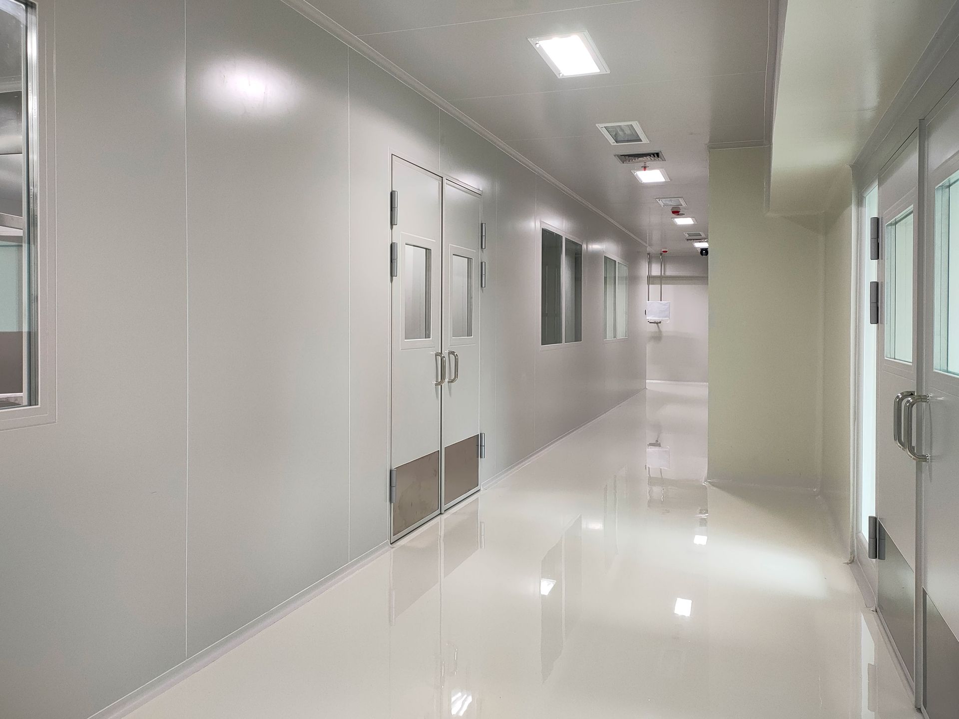 Bright white hospital hallway with closed doors and glossy floors