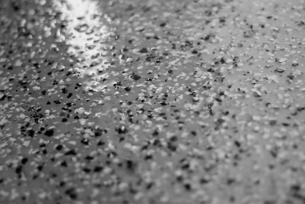 Close-up of a wet, speckled gray surface with scattered droplets or grains