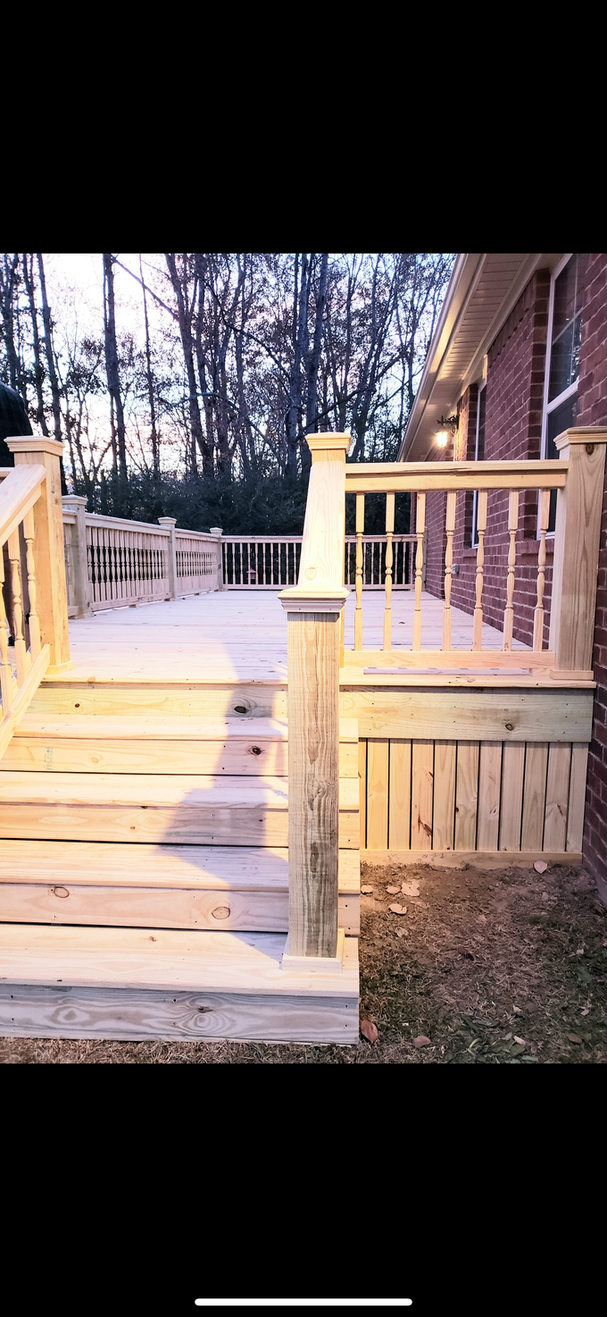 Wooden deck steps leading to a white-railed porch beside a house at dusk
