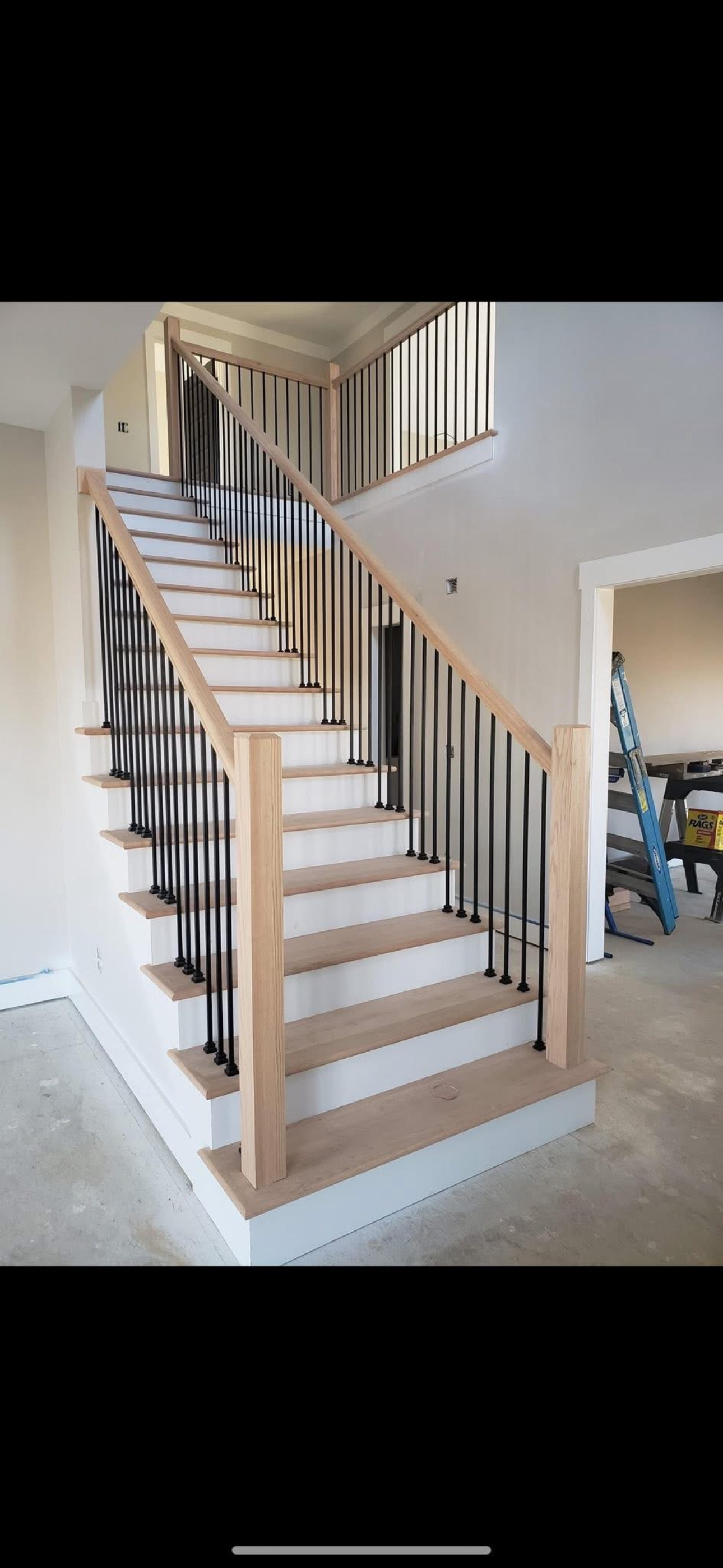 Indoor staircase with beige carpet, white walls, and dark wood railings, viewed from the bottom.