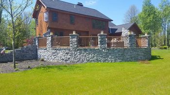 A large house with a large stone wall in front of it.