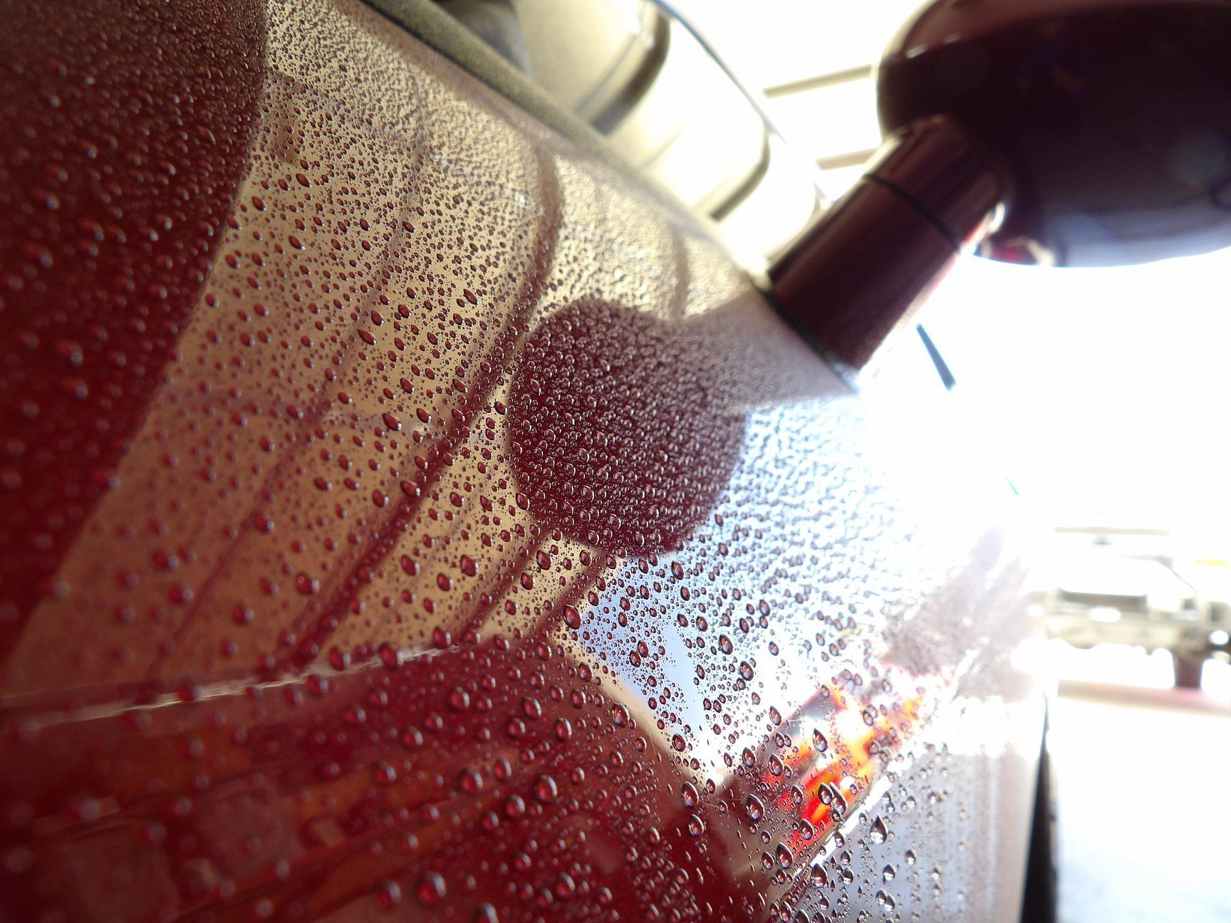 a close up of a red car with water drops on it